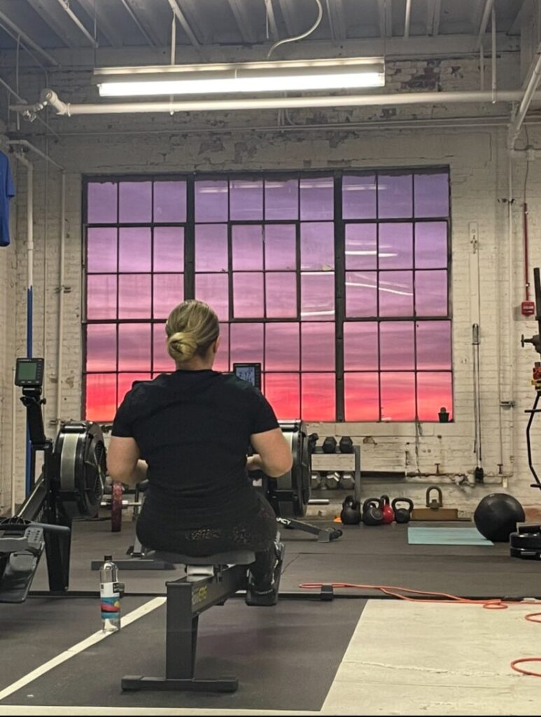 girl on row machine at sunset | group fitness classes