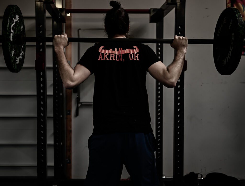 Man in front of squat bar | personal trainer near me | Shirt says Akron, OH