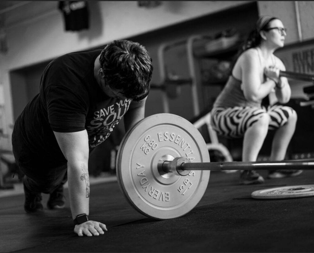 Group fitness classes near me | Man and woman performing squats and landmine workouts